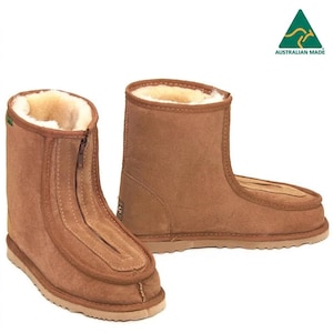 May include: A pair of tan suede ankle boots featuring a front-facing zipper closure, a cream-colored shearling lining, and a textured rubber sole. The boots display an Australian Made logo in the upper right corner with a green kangaroo icon.