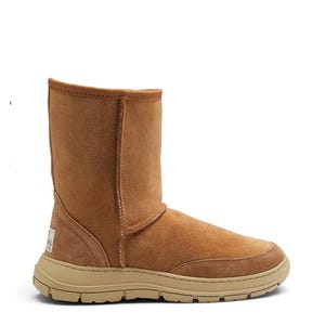 May include: A tan suede mid-calf boot featuring a rounded toe, a vertical seam running up the shaft, and a thick, textured beige rubber sole. A small rectangular brand label is stitched onto the lower heel area of the boot's exterior.