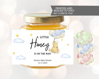 May include: A small jar of honey with a label that says "A Little Honey Is On The Way!"  Aliona's Baby Shower 12.17.2023. The label also features a cartoon Winnie the Pooh character holding balloons.