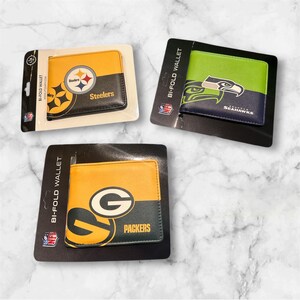 May include: Three bi-fold wallets featuring NFL team logos. One wallet is yellow and black with the Steelers logo, another is green and navy with the Seahawks logo, and the third is yellow and green with the Packers logo.