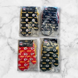 May include: Four sets of NFL oven mitts and pot holders. Each set features a different team logo: Steelers, Patriots, Chiefs, and Packers. The mitts and holders are black, navy blue, red, and green with the team's logo and name repeated in a pattern.