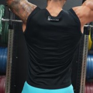 May include: A black sleeveless workout shirt with a small white logo on the upper back. The shirt is worn by a person lifting weights in a gym. The person's arms are raised, and the focus is on the shirt's design and fit.