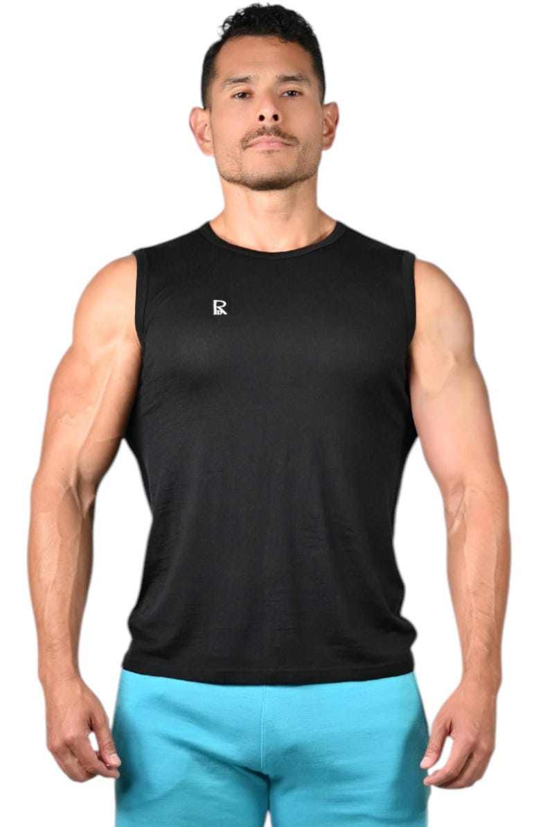 May include: Black sleeveless athletic shirt with a small white logo on the chest. The shirt is paired with light blue athletic shorts. The model is standing in front of a white background. The shirt is made of a lightweight, breathable material.