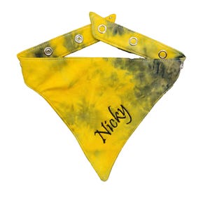 Puede incluir: Bandana para perros amarilla y negra teñida con la técnica tie-dye con el nombre "Nicky" bordado en negro. La bandana tiene correas ajustables con cierres a presión de metal para un ajuste seguro. Un accesorio elegante para mascotas.