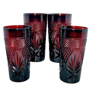 May include: Four ruby red drinking glasses with a diamond and leaf pattern. The glasses are tall and cylindrical, with a dark red color that fades to a lighter shade at the top. The glasses are made of glass and are suitable for serving beverages.