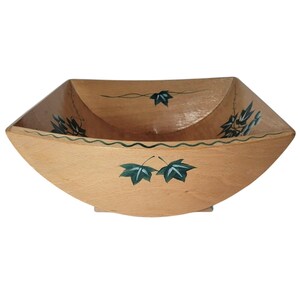 May include: A light-colored wooden bowl with a square shape and rounded sides. The bowl is decorated with green ivy leaf designs around the rim and on the interior. The bowl has a natural wood grain finish.