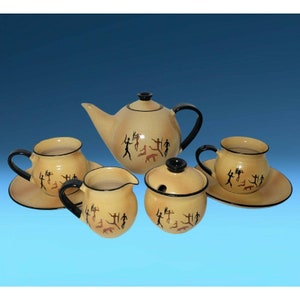 May include: A ceramic tea set with a brown and black design of stick figures and animals. The set includes a teapot, creamer, sugar bowl, and two cups and saucers.