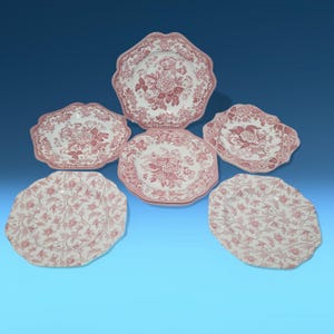 May include: Set of six pink and white floral patterned ceramic dinner plates with scalloped edges.