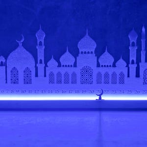 May include: White silhouette of a mosque with a blue LED light strip at the base. The silhouette includes a crescent moon and numbers 1 through 30.