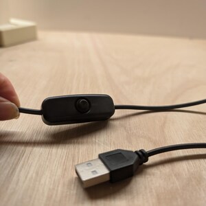 May include: A black USB cable with an inline on/off switch. The cable is connected to a USB plug.