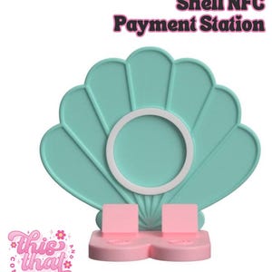 May include: A teal shell-shaped NFC payment station with a white circular center and pink base. The text "Shell NFC Payment Station" is at the top. The logo "This That Company" is at the bottom left.