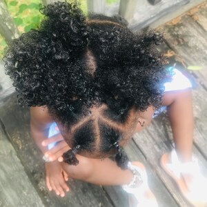 Puede incluir: Una ni&ntilde;a peque&ntilde;a con el pelo negro rizado peinado en cuatro mo&ntilde;os. La ni&ntilde;a lleva una camisa azul claro y sandalias blancas.