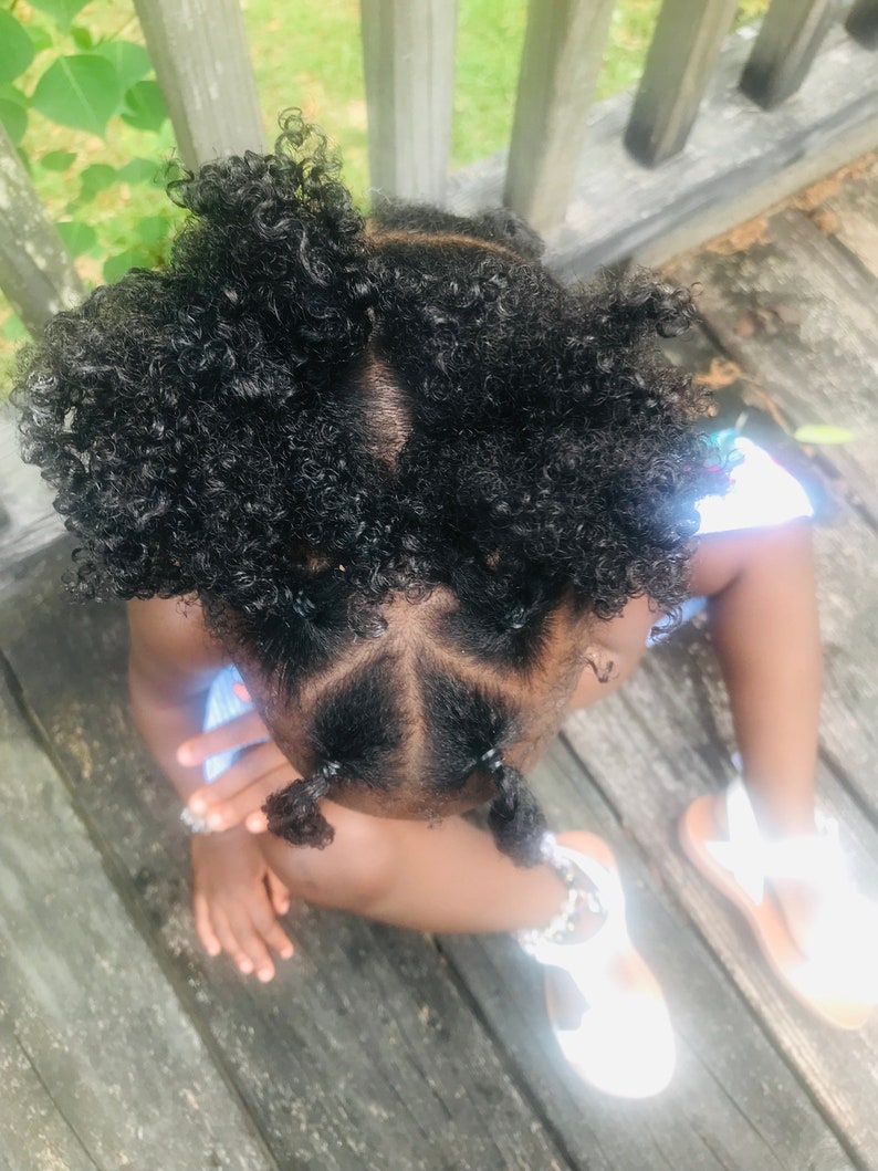 Puede incluir: Una ni&ntilde;a peque&ntilde;a con el pelo negro rizado peinado en cuatro mo&ntilde;os. La ni&ntilde;a lleva una camisa azul claro y sandalias blancas.