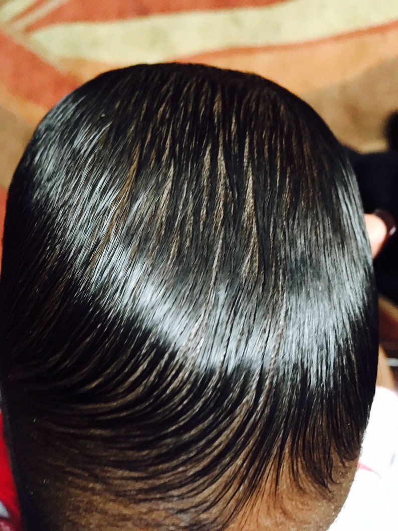 Puede incluir: Primer plano de la cabeza de una persona con cabello negro peinado hacia atr&aacute;s, liso y brillante.