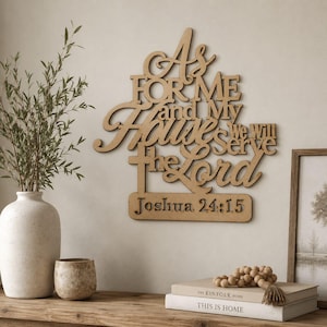 May include: A light brown wooden wall sign featuring the laser-cut text As For Me and My House we will serve the Lord with the reference Joshua 24:15 displayed on a rectangular base. The sign has a smooth finish and a flat, layered appearance.