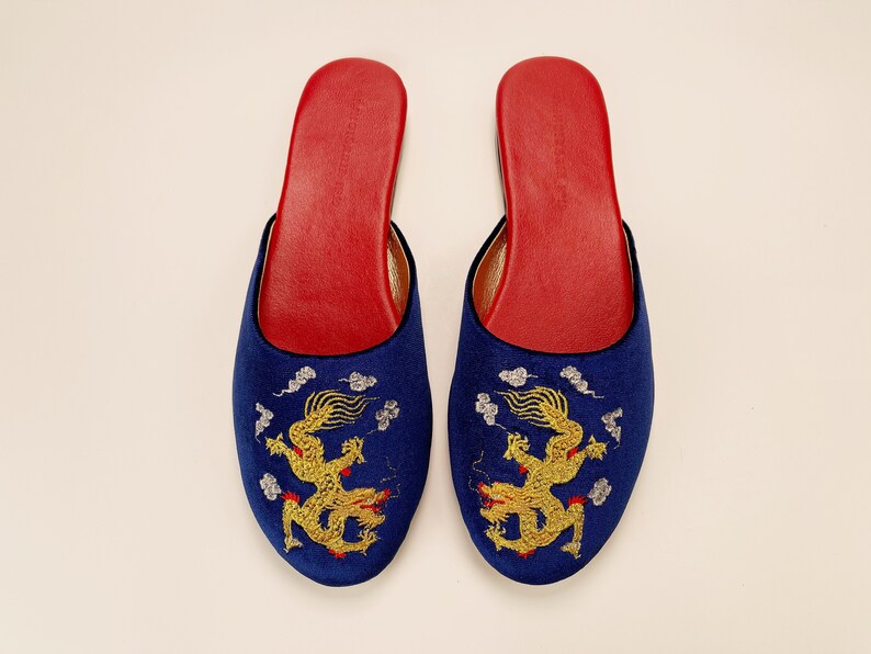 May include: A pair of blue satin slippers with gold embroidered dragons and red accents.