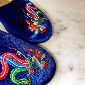 May include: A pair of blue satin slippers with colorful embroidered phoenix designs.