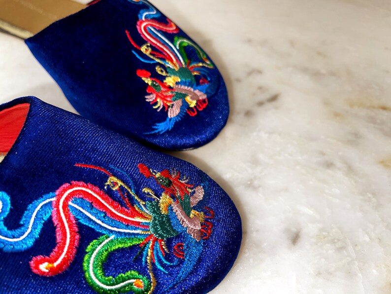 May include: A pair of blue satin slippers with colorful embroidered phoenix designs.
