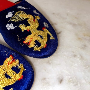 May include: A pair of blue velvet slippers with gold embroidered dragons. The slippers have red trim.