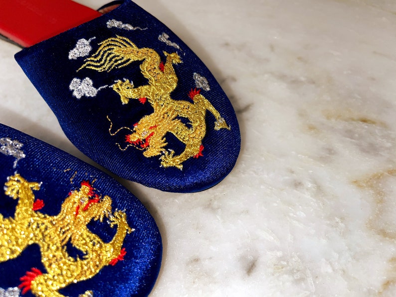May include: A pair of blue velvet slippers with gold embroidered dragons. The slippers have red trim.