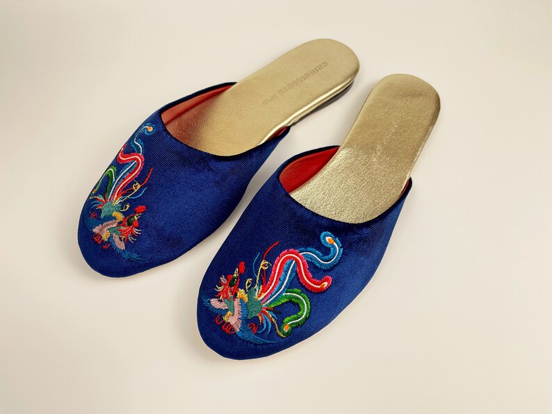 May include: A pair of blue velvet slippers with embroidered phoenix designs in red, green, and yellow. The slippers have a gold insole.