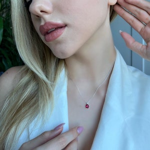 May include: A silver necklace with a teardrop-shaped red gemstone pendant.