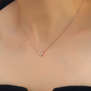 May include: A delicate gold chain necklace with a small letter 'M' pendant.