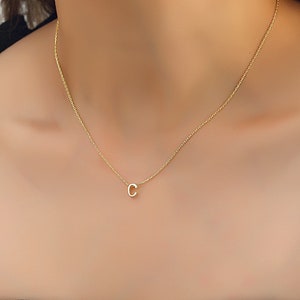 May include: A gold chain necklace with a small letter 'C' pendant.