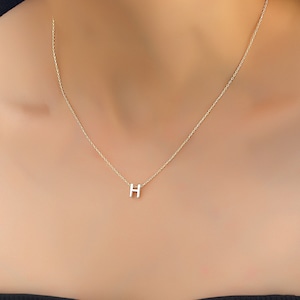 May include: A gold chain necklace with a small letter H pendant.