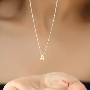 May include: A gold chain necklace with a small gold letter A pendant.