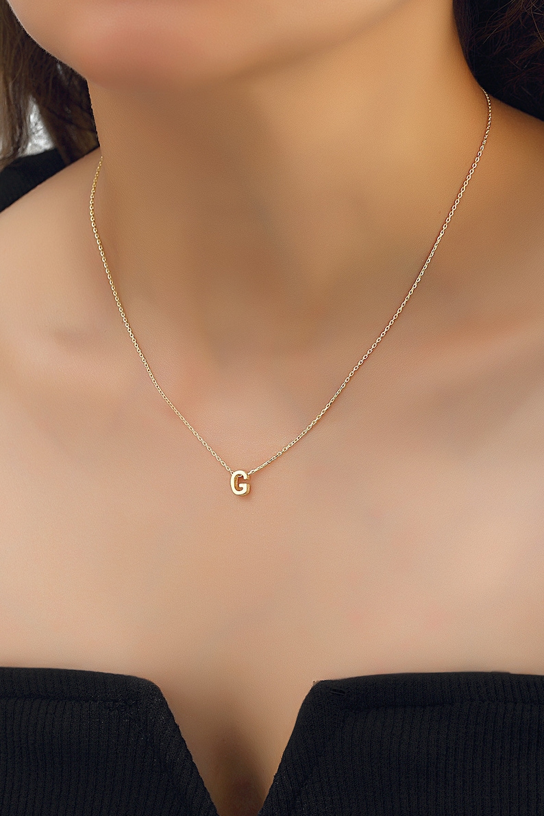 May include: A gold chain necklace with a small gold letter G pendant.
