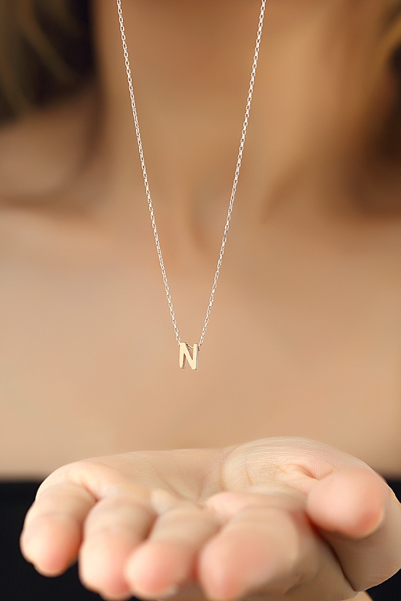 May include: A delicate gold chain necklace with a small gold letter N pendant.