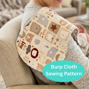 May include: A beige burp cloth with a repeating pattern of cartoon bears, stars, and text. The text includes phrases like "Little Man" and "Big Bear". The cloth is curved and has a blue oval with the text "Burp Cloth Sewing Pattern".