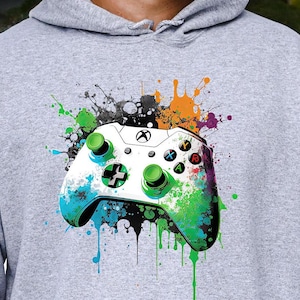 May include: A gray hoodie with a white and green video game controller graphic. The controller is surrounded by colorful paint splatters.