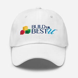 May include: White baseball cap with the text "BUILD UR BEST U" in blue, with colorful block graphics. The cap has a curved brim and a button on top.