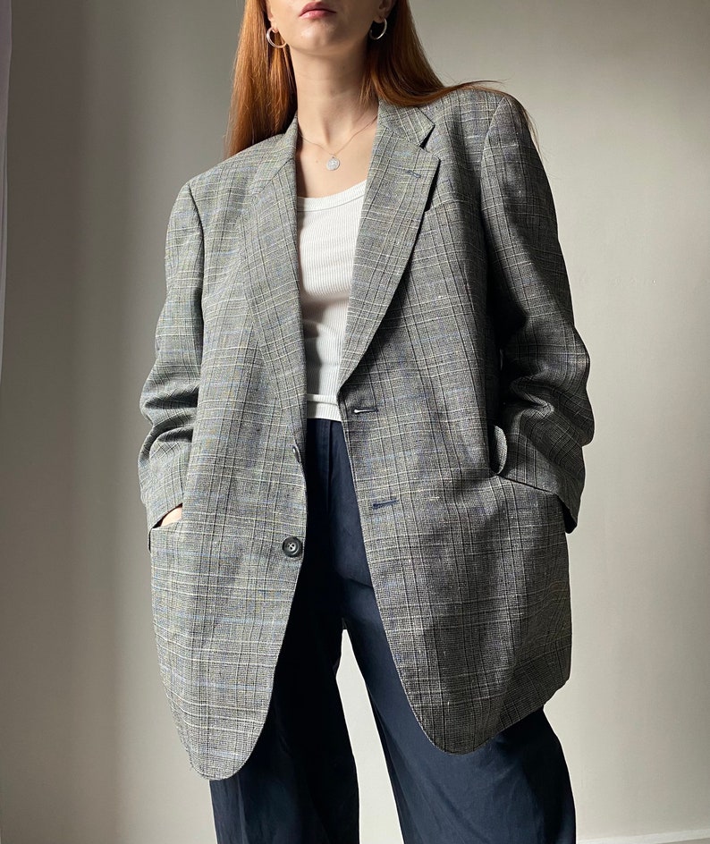 Vintage check blazer would fit a size medium well. Black, white and blue checks but looks grey from a distance. 70% polyester, 30% hemp, fabric made in Italy. Single breasted double button fastening with inner & outer pockets.