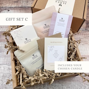 A gift set containing a box, a card, and a card holder, all with the brand name "ALBYSTONE" printed on them. The box is filled with brown paper, and there is a card inside the box.