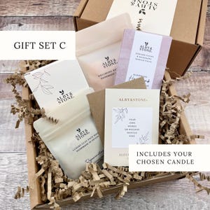 A gift set containing a box, a card, and a card holder, all with the brand name "ALBYSTONE" printed on them. The box is filled with brown paper, and there is a card inside the box.