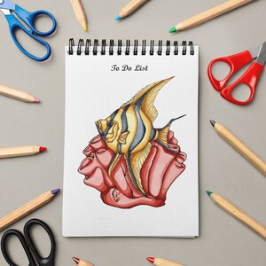 May include: A white notebook with a spiral binding and the words "To Do List" written on the front. The notebook has a drawing of a yellow and black angelfish on a red coral reef.