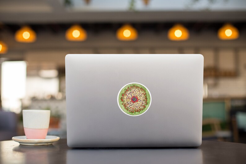 May include: A laptop computer with a sticker of a colorful mandala design on the lid. The mandala is green, red, yellow, and white.