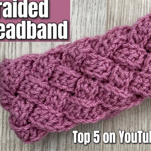 May include: A close-up of a pink crocheted headband with a braided design. The headband is made with five strings of yarn and is shown on a wooden surface. The text "Braided Headband" and "Top 5 on YouTube" is visible in the image.
