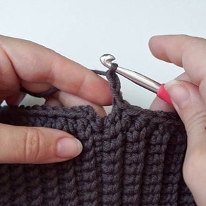 Crocheting Turtleneck Hoodie in brown Wool yarn on a styrofoam head.