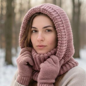Könnte beinhalten: Ein Strick-Set aus Kapuze und Handschuhen in Staubrosa. Die Kapuze hat ein Rippenmuster und einen integrierten Schal, der Wärme und Stil bietet. Die Handschuhe, in der gleichen Farbe und Textur, vervollständigen das koordinierte Winter-Accessoire-Set.