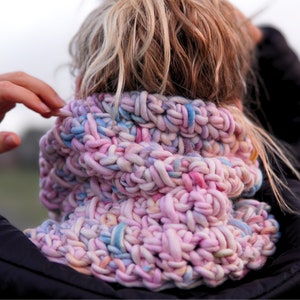 Può includere: Un collo a scialle in maglia grossa rosa, blu e bianco. La sciarpa è realizzata in filato morbido ed è perfetta per tenersi al caldo in inverno.
