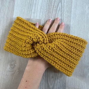 May include: A mustard yellow knitted headband with a twisted knot design.