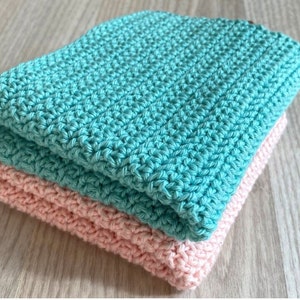 Peut inclure: Deux torchons en crochet, l'un turquoise et l'autre rose, sont empilés l'un sur l'autre.