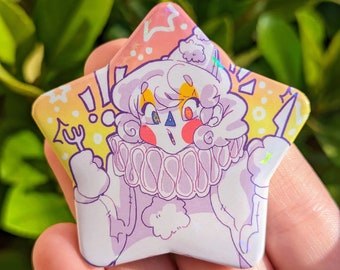 May include: A star-shaped button with a holographic finish features a cartoon illustration of a white clown with a pink face, yellow hair, and a purple ruffle collar. The clown is holding a fork and has an exclamation point above its head. The background is a gradient of pink, yellow, and white with white dots and a lightning bolt.