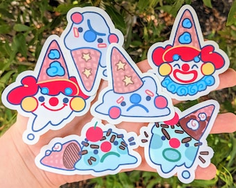 May include: Five colorful stickers featuring ice cream cones with different facial expressions. The stickers are on a hand, and the ice cream cones are all different colors and have different toppings.