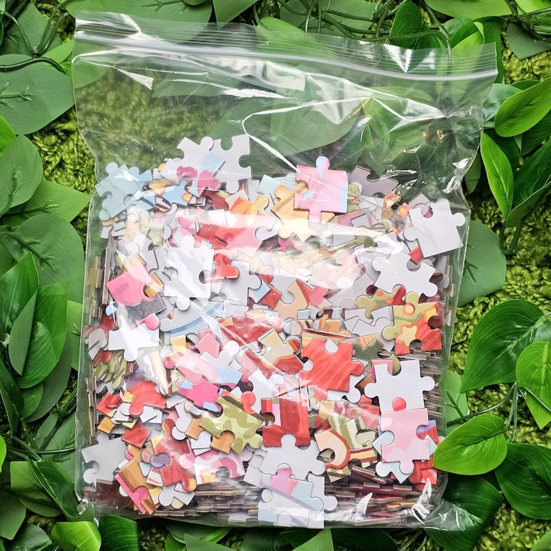 May include: A plastic bag filled with colorful jigsaw puzzle pieces. The pieces are various shapes and sizes and have a variety of images printed on them.