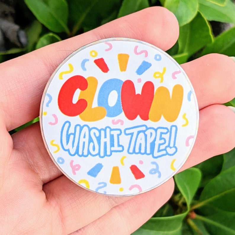 May include: A round sticker with a white background and colourful confetti. The sticker says "Clown Washi Tape!" in a colourful, playful font.